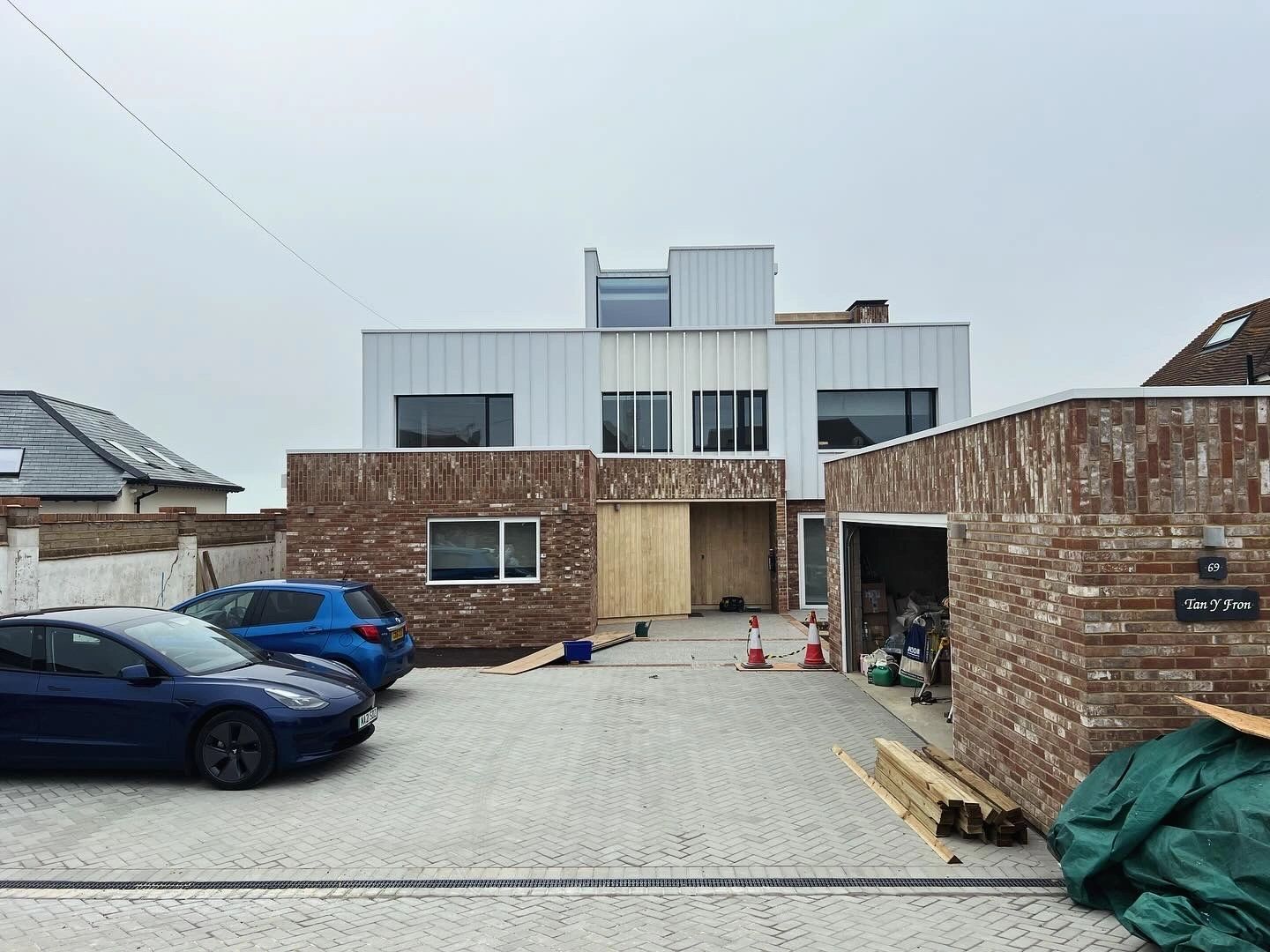 A modern house front with brick and white cladding, under construction